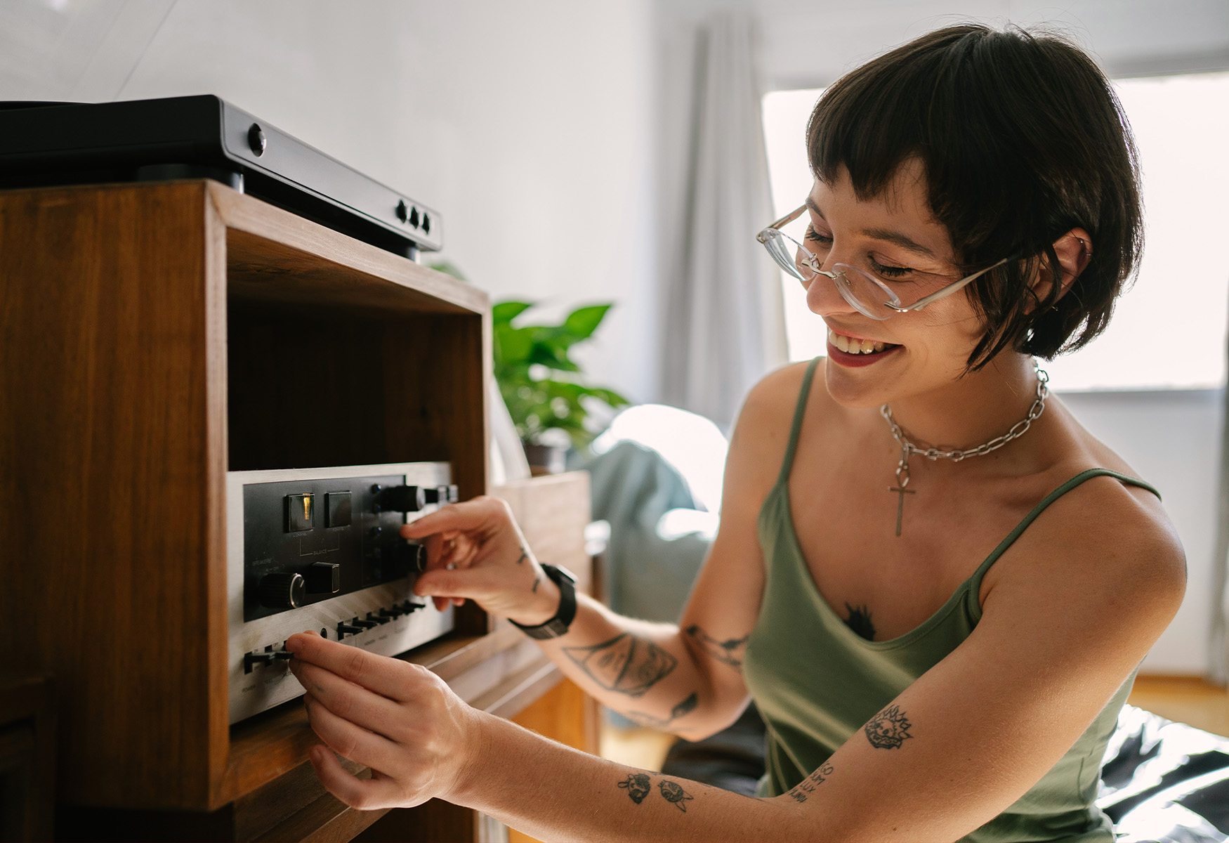 06-Section-6_IMG_01 Smiling woman adjusting the dials on a vintage stereo receiver
